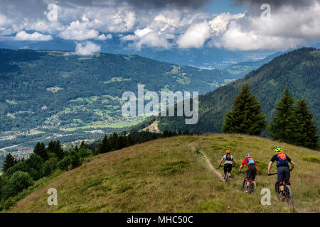 A group of men on mountain bikes ride a trail along a ridge near the Col de Joux Plane in the direction of the French alpine town of Samoëns. Stock Photo