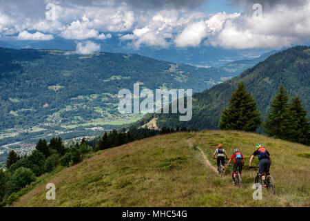 A group of men on mountain bikes ride a trail along a ridge near the Col de Joux Plane in the direction of the French alpine town of Samoëns. Stock Photo