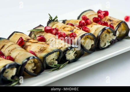 Eggplant with nuts. Delicious fried eggplant appetizer with nuts, herbs and pomegranate seeds. Georgian cuisine dish on white plate on white background Stock Photo