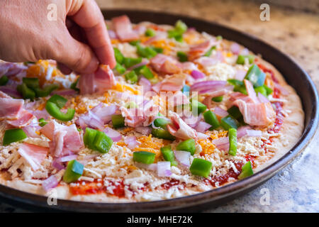 Making pizza. Cook's hand sprinkles bacon. American style, cooking in a baking dish Stock Photo