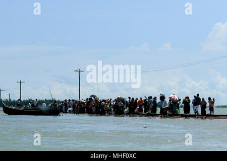 Rohingya refugees, who arrived from Myanmar crossing the Naf River by boat, walk towards a refugee camp at Shah Porir Dweep. Teknaf, Cox's Bazar, Bang Stock Photo