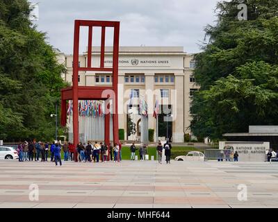 Visitors gather around the sculpture “Broken Chair,” on the Plaza of Nations, Geneva, Switzerland. Stock Photo