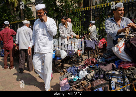 Some of the 5,000 Dabbawalas, dressed in the obligatory white Gandhi caps preparing to deliver some of 130,000 lunch boxes delivered to offices every morning and returned home every afternoon 6 days a week 51 weeks a year. The service provides home cooked food to delivered from home to office and back home again. The service is claimed to make less than one mistake in 6 million deliveries. Mumbai, India. photo by  Mike Abrahams Stock Photo