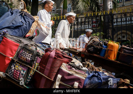 Some of the 5,000 Dabbawalas, dressed in the obligatory white Gandhi caps preparing to deliver some of 130,000 lunch boxes delivered to offices every morning and returned home every afternoon 6 days a week 51 weeks a year. The service provides home cooked food to delivered from home to office and back home again. The service is claimed to make less than one mistake in 6 million deliveries. Mumbai, India. photo by  Mike Abrahams Stock Photo