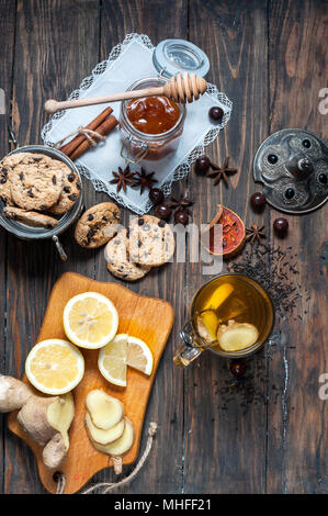 Dried tea with lemon and cookies on wooden table. Stock Photo