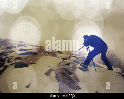 Abstract effect.  Travel photographer doing pictures in ancient stones on snowy peak of mountain. Winter cold and misty morning in mountains Stock Photo