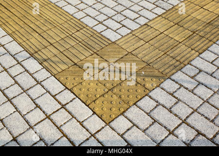 Sidewalk guides for blind. Yellow concrete cobblestones on walkway for blindness people Stock Photo