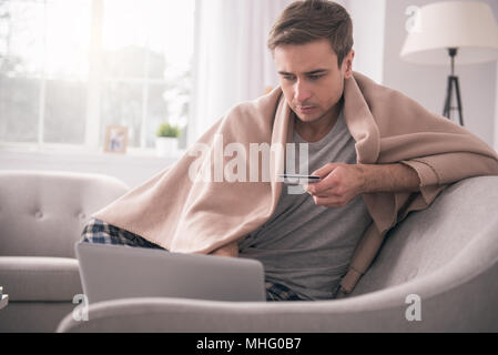 Pleasant good looking man holding his credit card Stock Photo