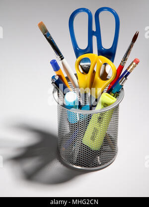 Pens, pencils, scissors and brushes in a pot, on a white background. Stock Photo