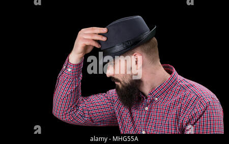 Pensive  bearded male dressed in a fleece shirt  and hat posing over black background. Stock Photo