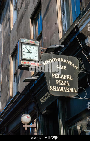 EDINBURGH, SCOTLAND- NOVEMBER 11th 2009:  An old town clock with an old cigar maker on it. Next to it a Mediterranean sign in Edinburgh. Stock Photo