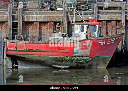 A fishing boat sits grounded at her moorings by the low tide in Scarborough’s harbour. Stock Photo