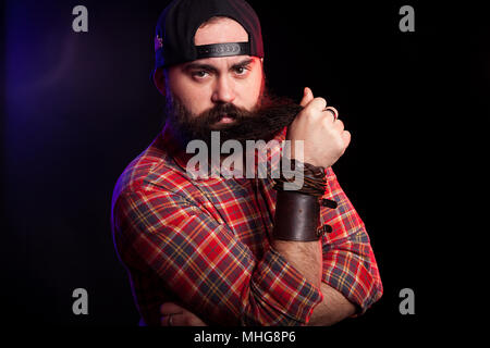 Angry bearded hipster man holding his beard in hands Stock Photo