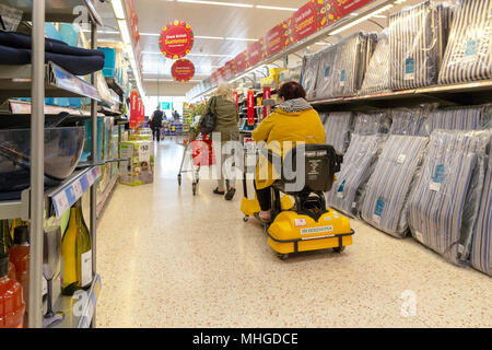 A lady on a Mart Cart and a lady pushing a trolley in Morrisons supermarket in Stockton Heath, near Warrington, Cheshire, England, UK on 30 April 2018 Stock Photo