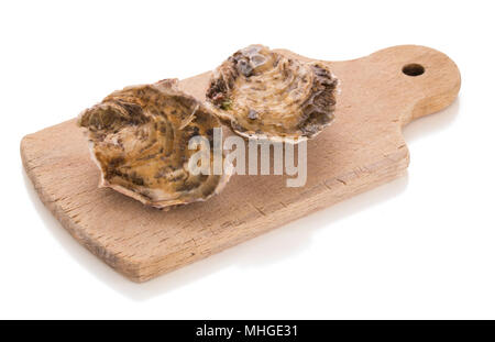 Two closed oyster on a wooden cutting board isolated on a white background Stock Photo