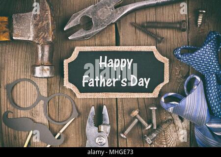 Happy Fathers Day message on a chalkboard tag with frame of tools and ties on a wooden background, vintage styling Stock Photo