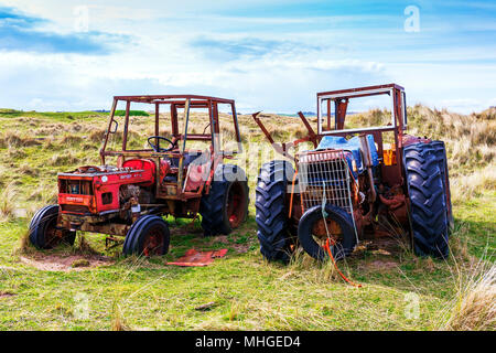 Two old and abandoned farm tractors in a field near Goswick, Northumberland, England, UK Stock Photo