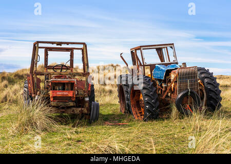 Two abandoned and rusting farm tractors in a field near Goswick, Northumberland, England Stock Photo
