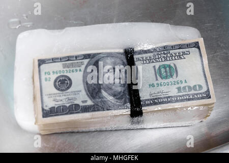 bundle of hundred-dollar bills frozen in ice Stock Photo