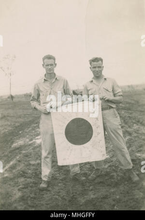 Antique 1944 photograph, two American soldiers hold a Japanese Good Luck Flag in New Guinea. SOURCE: ORIGINAL PHOTOGRAPHIC PRINT. Stock Photo