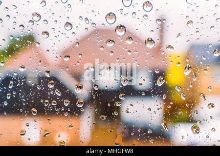 colourful abstact image of defocused houses through a window with rain drops. The reflection of the houses can be seen in the water drops Stock Photo