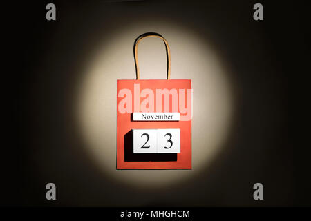 Red shopping bag with Black Friday date in the ray of scenic spot light over dark background. Stock Photo