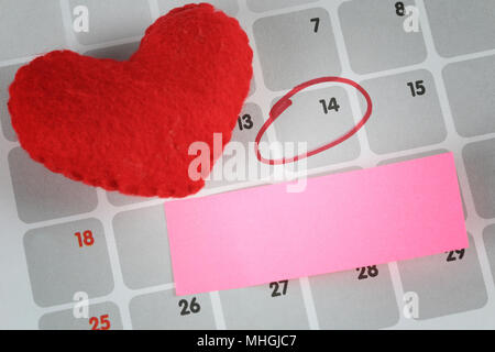 Red heart and pink paper note is placed on the calendar and focus in Fourteenth day for design in your festival of Love. Stock Photo