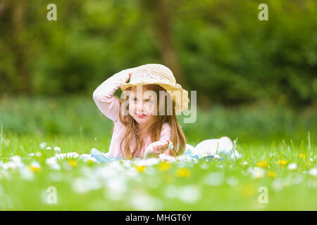 Four-year-old girl in the park in spring time lying on the grass Stock Photo