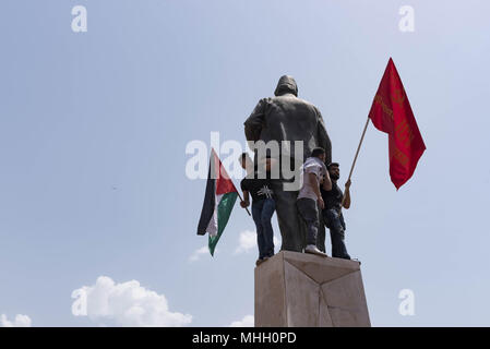 Beirut, Lebanon. 1st May, 2018. Two youth carrying a Palestinian flag (left) and a Communist flag (right) stand atop a statue of Riad al-Solh, Lebanon's first prime minister, during an International Workers' Day march organized by the Lebanese Communist Party and other worker rights groups. Credit: Antoine Abou-Diwan/SOPA Images/ZUMA Wire/Alamy Live News Stock Photo