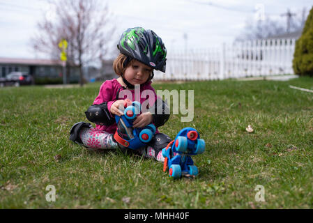 A little girl puts on her roller skates during the summer on a sunny day Stock Photo