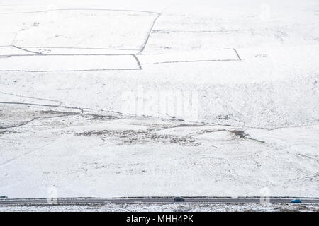 Cars on a road next to snow covered hillside fields at Peakshill in the Derbyshire countryside, Peak District, Britain, UK Stock Photo