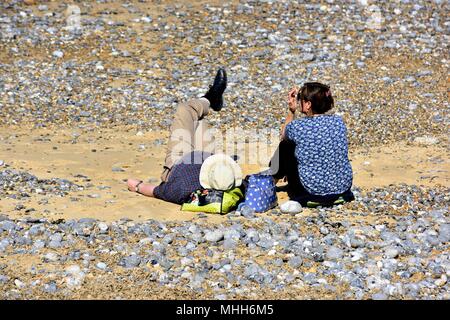 Middle aged couple relaxing on the pebble beach in Cromer Norfolk England UK Stock Photo