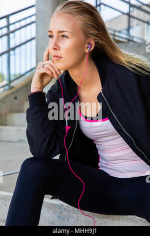 Thoughtful Fit Woman Listening To Music While Sitting On Steps