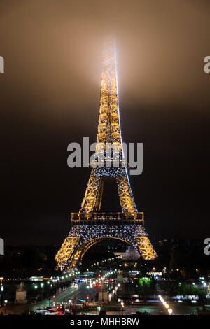 The Eiffel Tower at night with its summit in the fog / mist / clouds Stock Photo