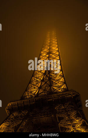 The Eiffel Tower at night with its summit in the fog / mist / clouds Stock Photo