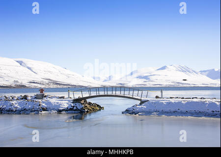 Pedestrian bridge in Akureyri with a view to Eyjafjordur, Iceland's longest fjord, with snowy mountains in the background Stock Photo