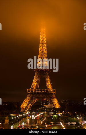 The Eiffel Tower at night with its summit in the fog / mist / clouds Stock Photo