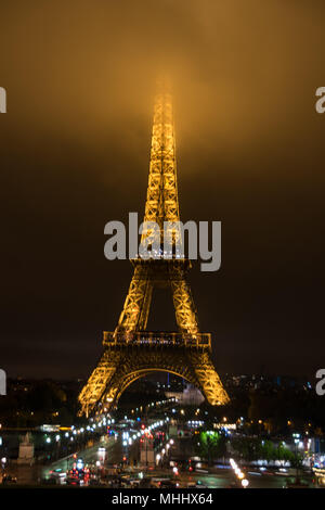 The Eiffel Tower at night with its summit in the fog / mist / clouds Stock Photo