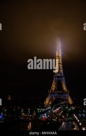 The Eiffel Tower at night with its summit in the fog / mist / clouds Stock Photo