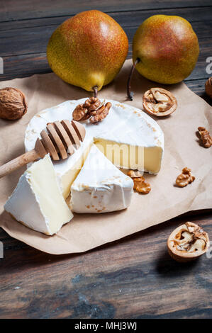 Camembert cheese with walnuts, honey and pears on rustic table. Stock Photo