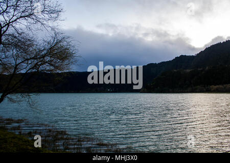 Peaceful lake surrounded by forest at dusk Stock Photo