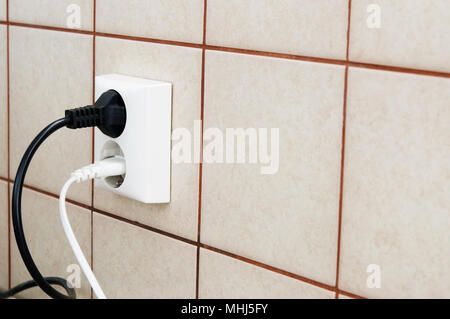 Plugs connected to the outlet in a wall. Stock Photo