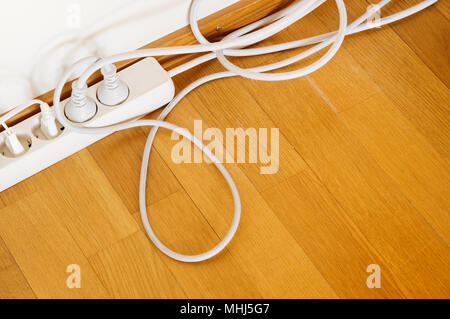 Multiple socket and plugs on wooden floor. Stock Photo