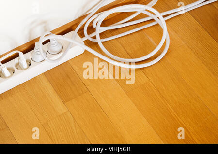 Multiple socket and plugs on wooden floor. Stock Photo