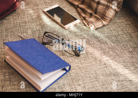 Eyeglasses on open notebook with smartphone. Working or planning concept. Stock Photo