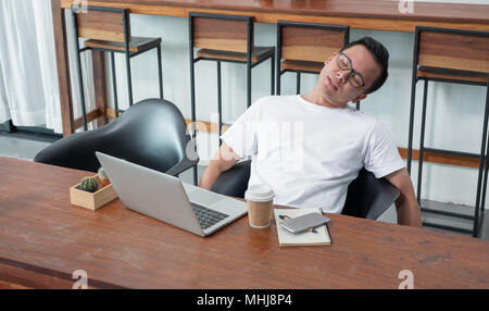 asia casual man sit back feel tired from work at laptop in coffee shop,stress business concept,work outside office,work at home Stock Photo