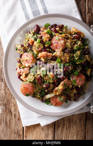Brazilian food: Feijao Tropeiro with beans, sausage and bacon close-up on a plate on the table. Vertical top view from above Stock Photo
