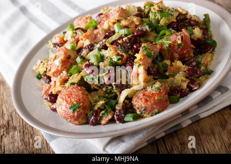 Brazilian traditional tropeiro fried beans with greens, sausages, bacon and eggs close-up on a plate on a table. horizontal Stock Photo