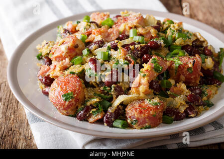 Brazilian beans with greens, sausages, bacon and eggs close-up on a plate on a table. horizontal Stock Photo