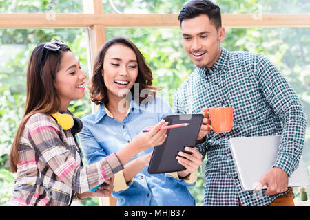 Three cheerful young employees working together on a project Stock Photo